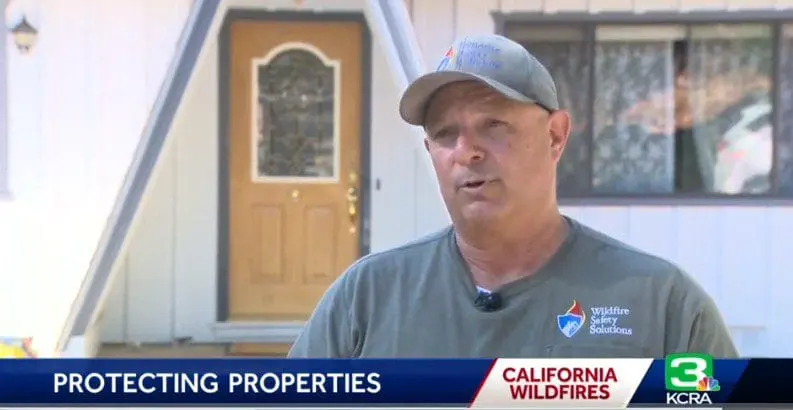 A man in a cap speaks outside a house; news banner reads PROTECTING PROPERTIES CALIFORNIA WILDFIRES.