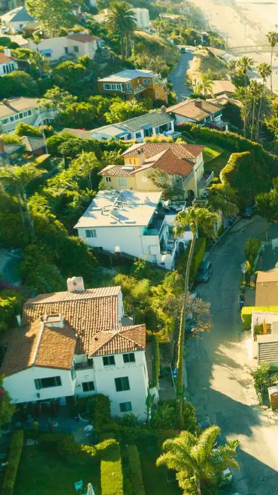 Aerial view of coastal houses lining a curved road on a sunny day.