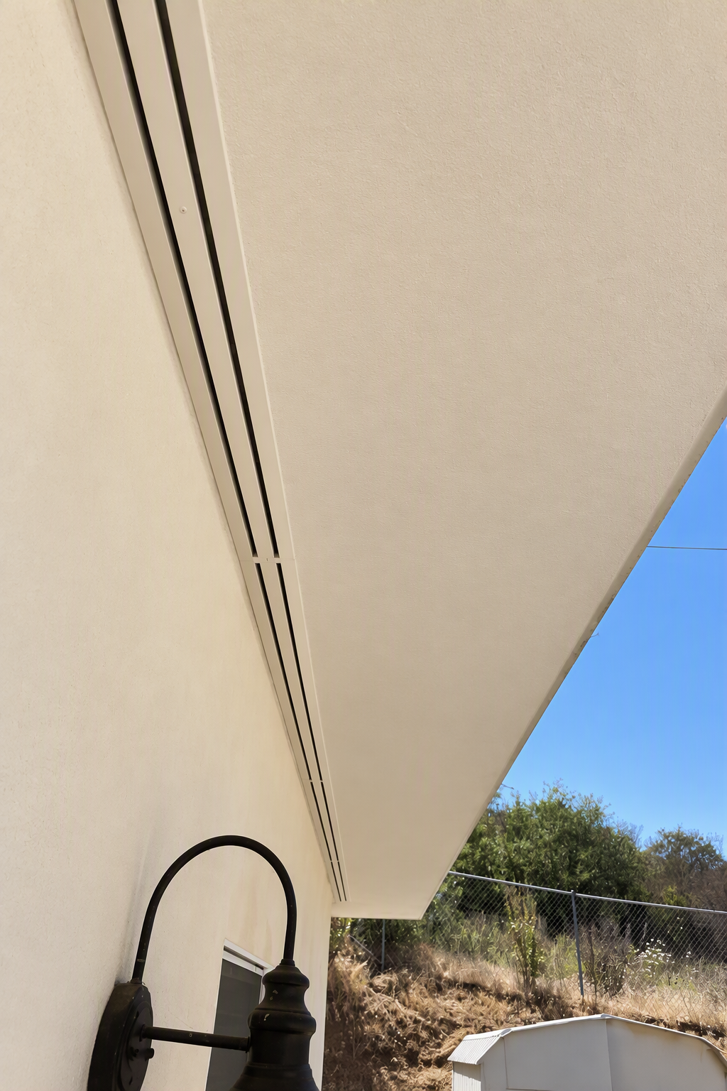 Linear slot diffuser vent in a beige ceiling overhang.