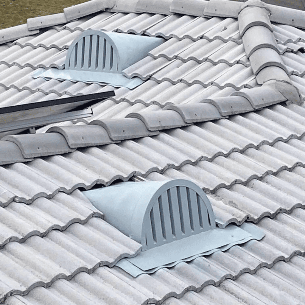 Gray tiled roof with two rounded attic vents featuring vertical slats, installed on the sloped surface.