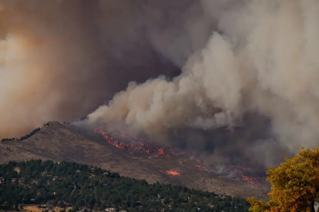Smoke-covered mountains in the distance; wildfire present.