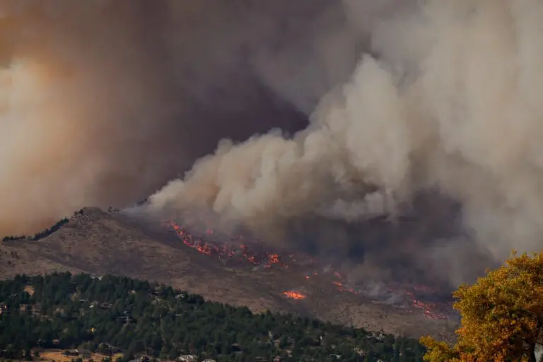 Smoke-covered mountains in the distance; wildfire present.