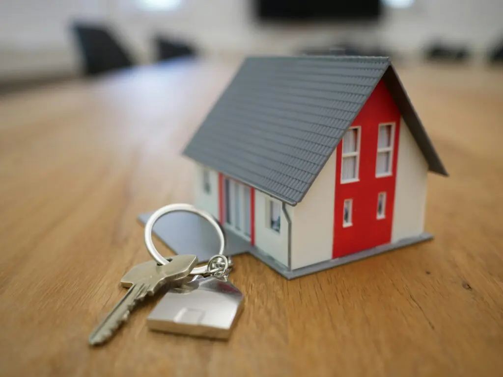 Model house on a wood table next to a set of house keys.