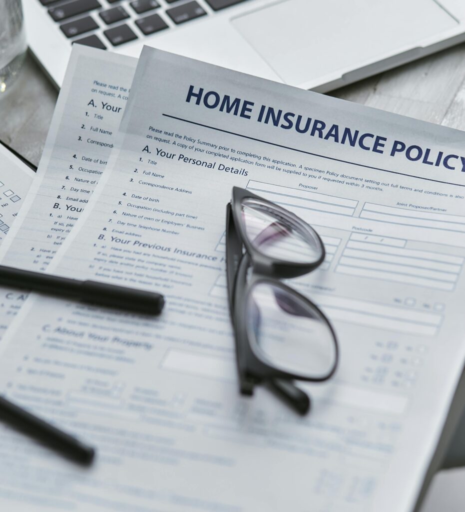 A blank homeowners insurance policy on a desk with a pair of black-framed glasses on top of the paperwork.