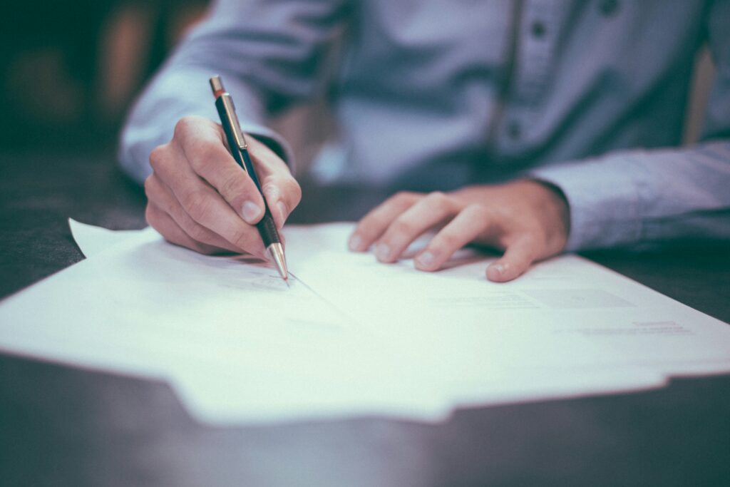 View of insurance agent's hands signing paperwork on a desk..
